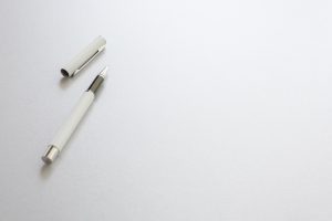 A white pen isolated on white writing paper, background.